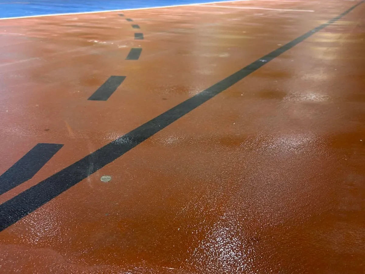 Pista del pabellón del Colegio Ciudad del Sol recién fregada, con el suelo naranja y azul brillando