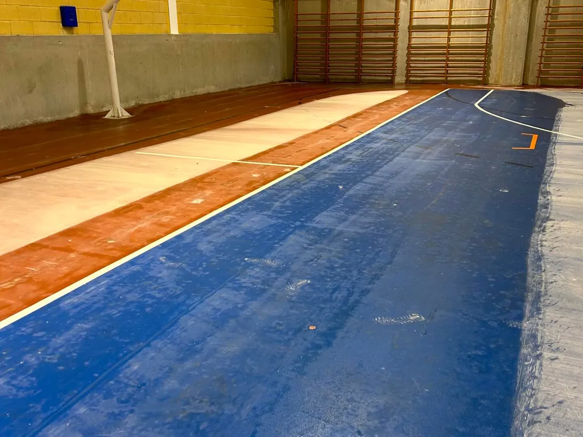 La fregadora avanzando por la pista azul del pabellón, con la canasta al fondo